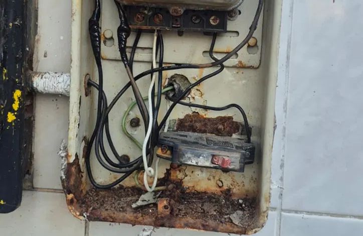 Caja de medidor antigua, oxidada y con cables enredados
