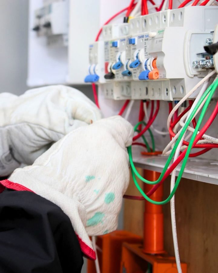 Manos con guantes conectando protecciones en un tablero
