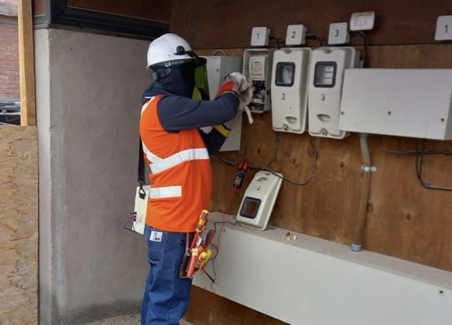 Técnico con casco, careta y guantes revisando medidores