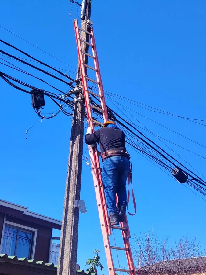 Técnico con casco y arnés subiendo a un poste